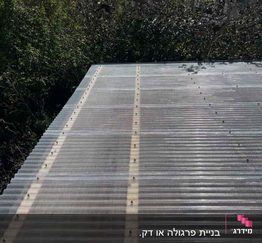 גג מתכת עם ברגים ועצים ברקע